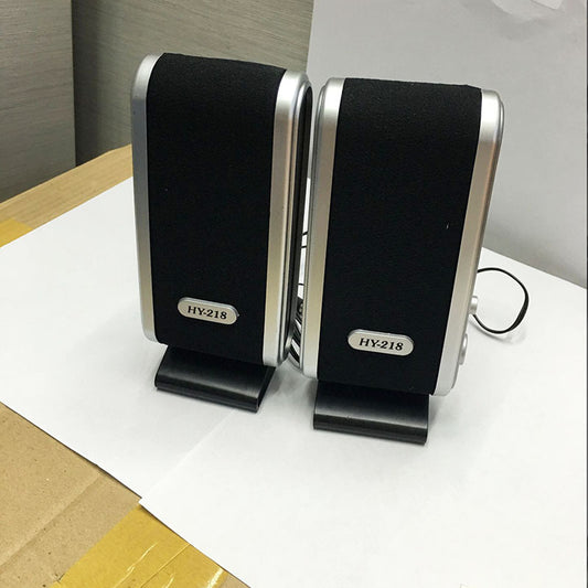 Pair of black and silver speakers on a white surface with a neutral background