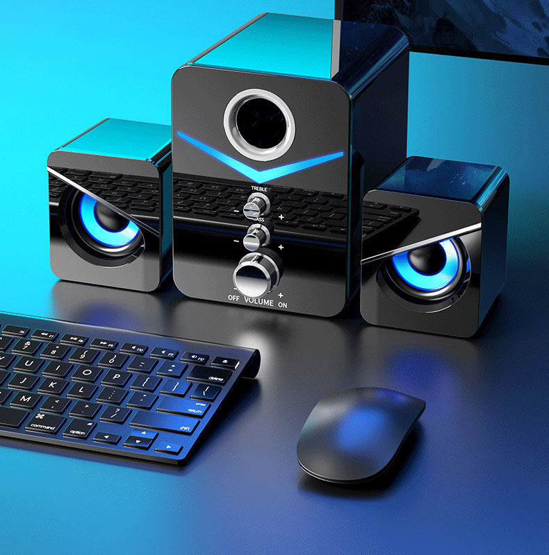 Black computer speakers with blue lights on a blue background, featuring a keyboard and mouse.