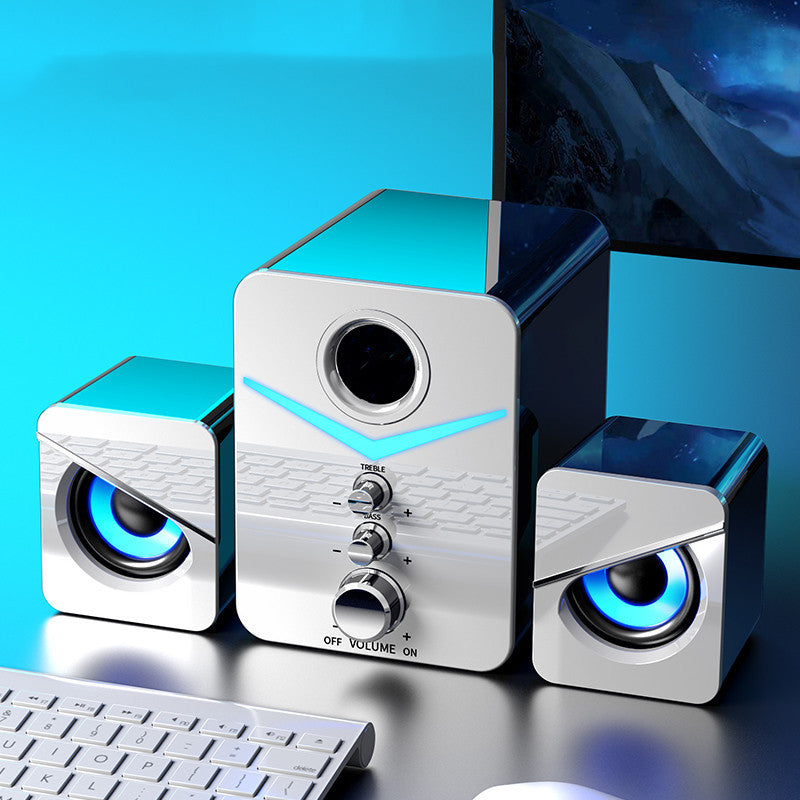 Set of three silver computer speakers with blue lights on a reflective surface.