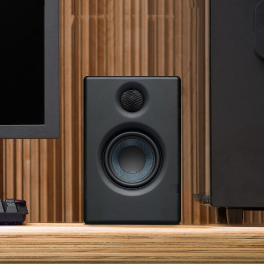 Black speaker on a wooden surface with a blurred background